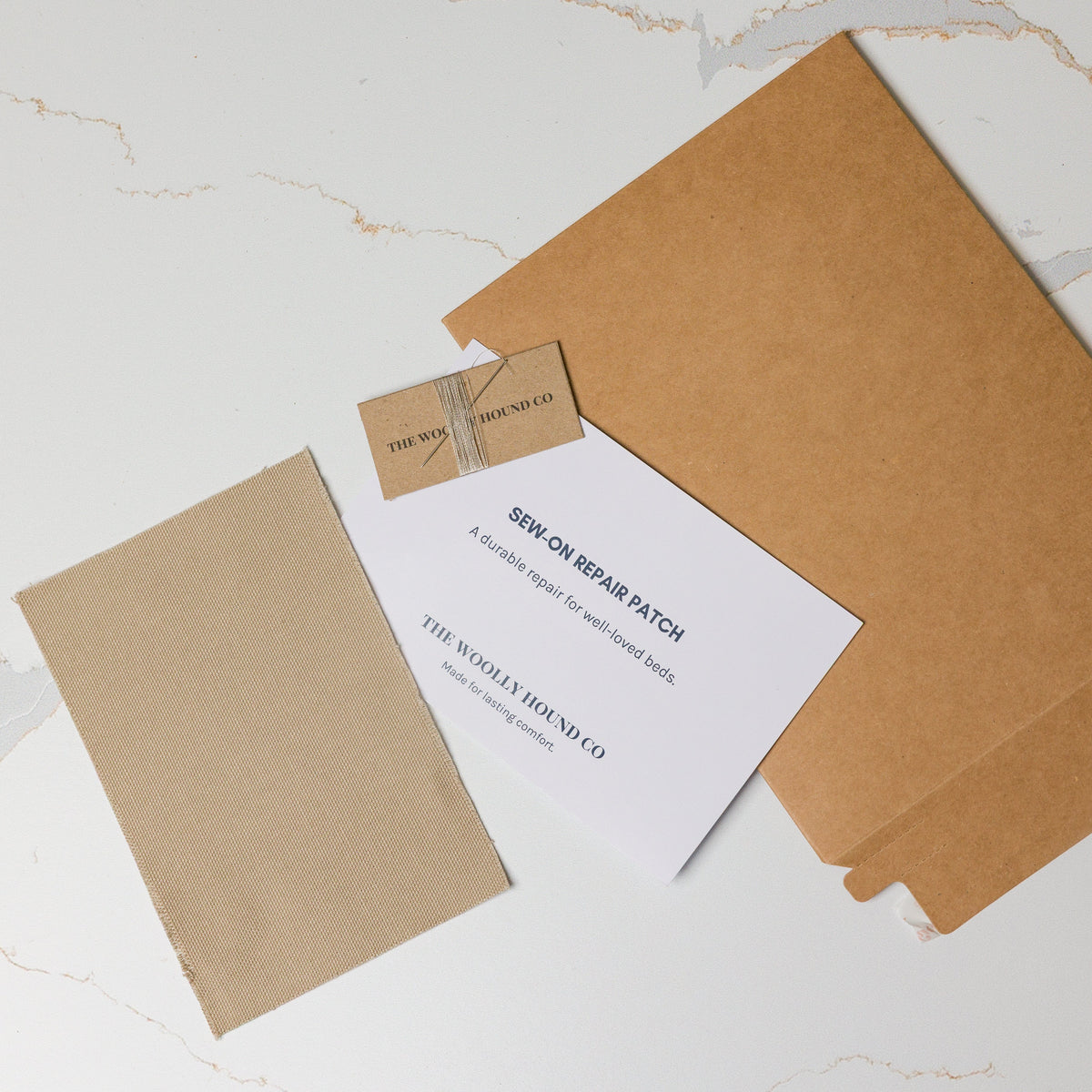 Sew-on bed repair patch kit including patch, thread, needle, and instruction card.