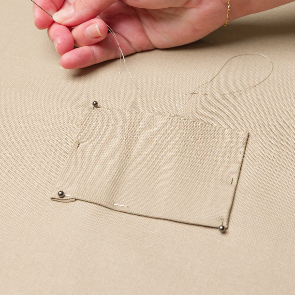 Hand sewing a repair patch onto a Classic Bed Cover.